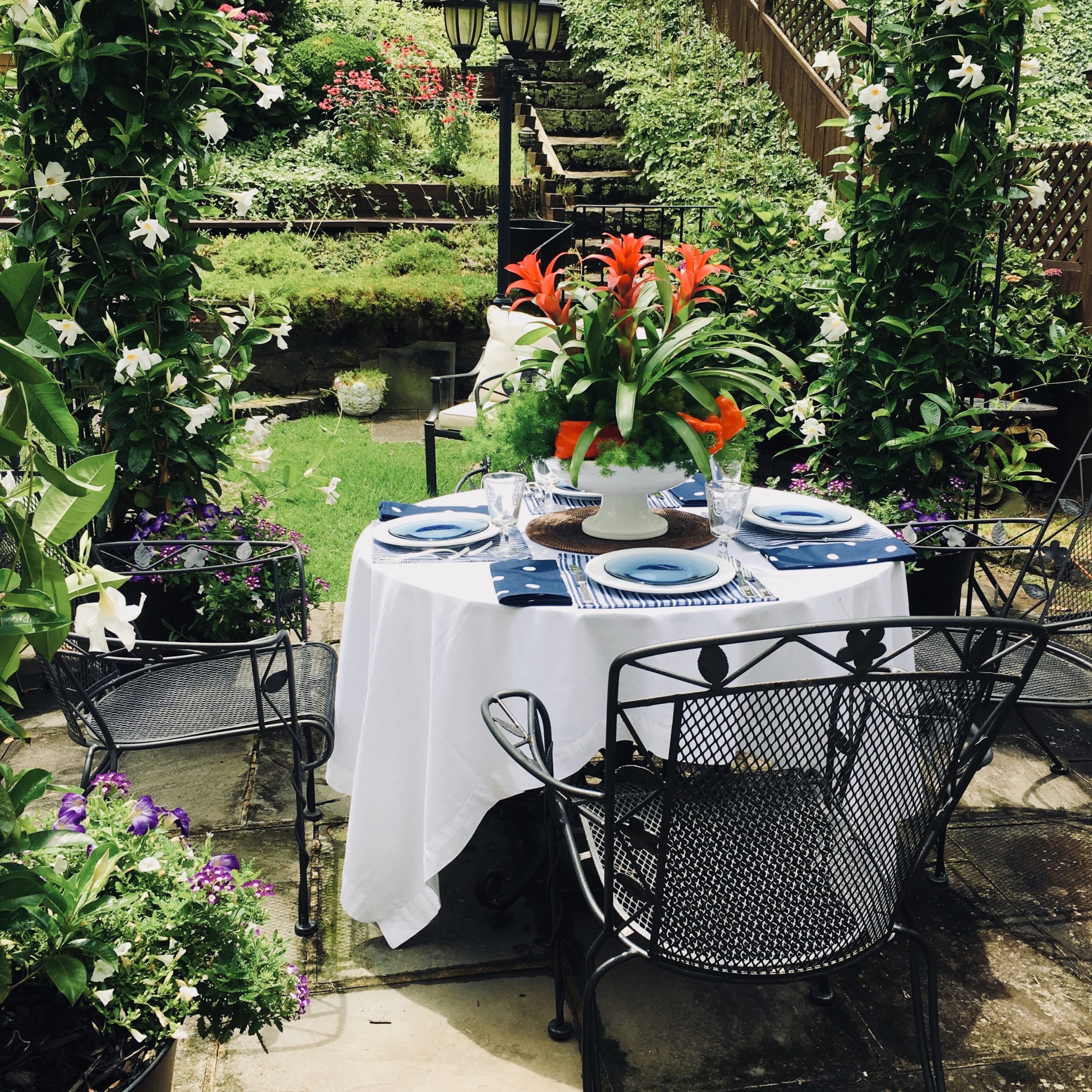 Memorial Day Table Setting in red white and blue with polkadot napkins and striped placemats, white dishes and red centerpiece
