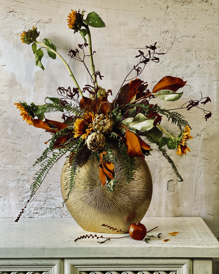 Flower arrangement featured in this article featuring russet sunflowers, dried artichokes, dried magnolia, dried kangaroo paw flowers