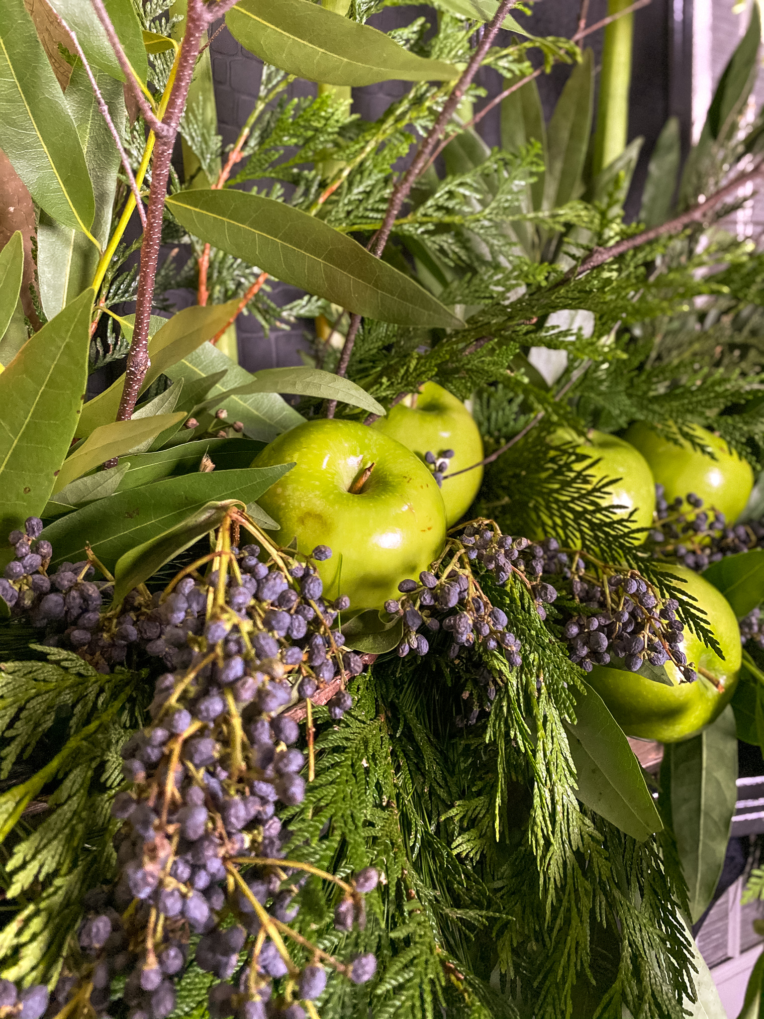 Green flowers and green apples on mantle with garlands to match