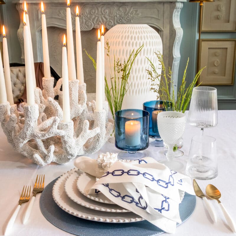 coral candelabra displayed on a table setting with blue and white elements. Coastal living type design